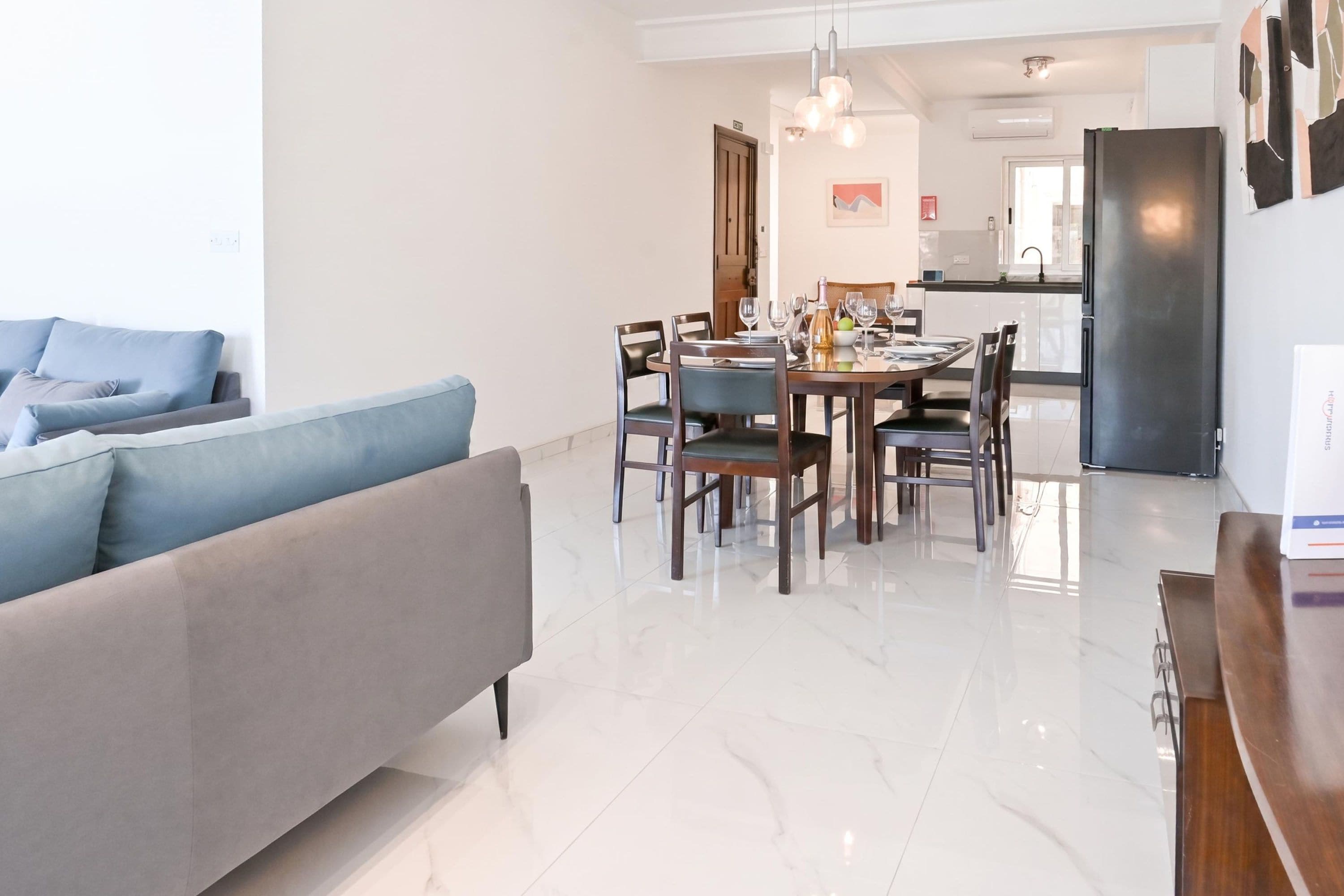 A modern living room with a sofa and a dining area with a table set for six.