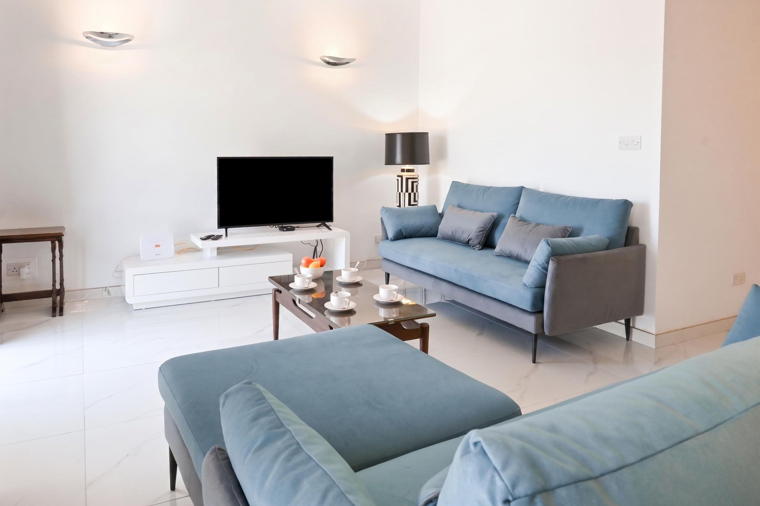 Een moderne woonkamer met een bank, een salontafel, een flatscreen televisie en een lamp.