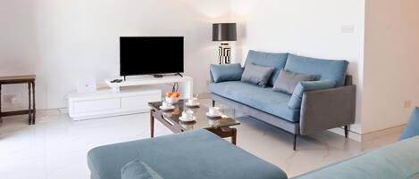 Een moderne woonkamer met een bank, een salontafel, een flatscreen televisie en een lamp.