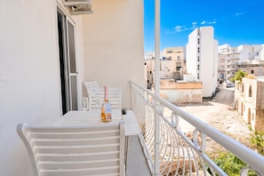 A balcony with a white table, a bottle of champagne, and a glass. The balcony overlooks a cityscape with buildings and a clear sky. - Yacht Marina View - Modern 3 Bdrs Apart M (Msida)