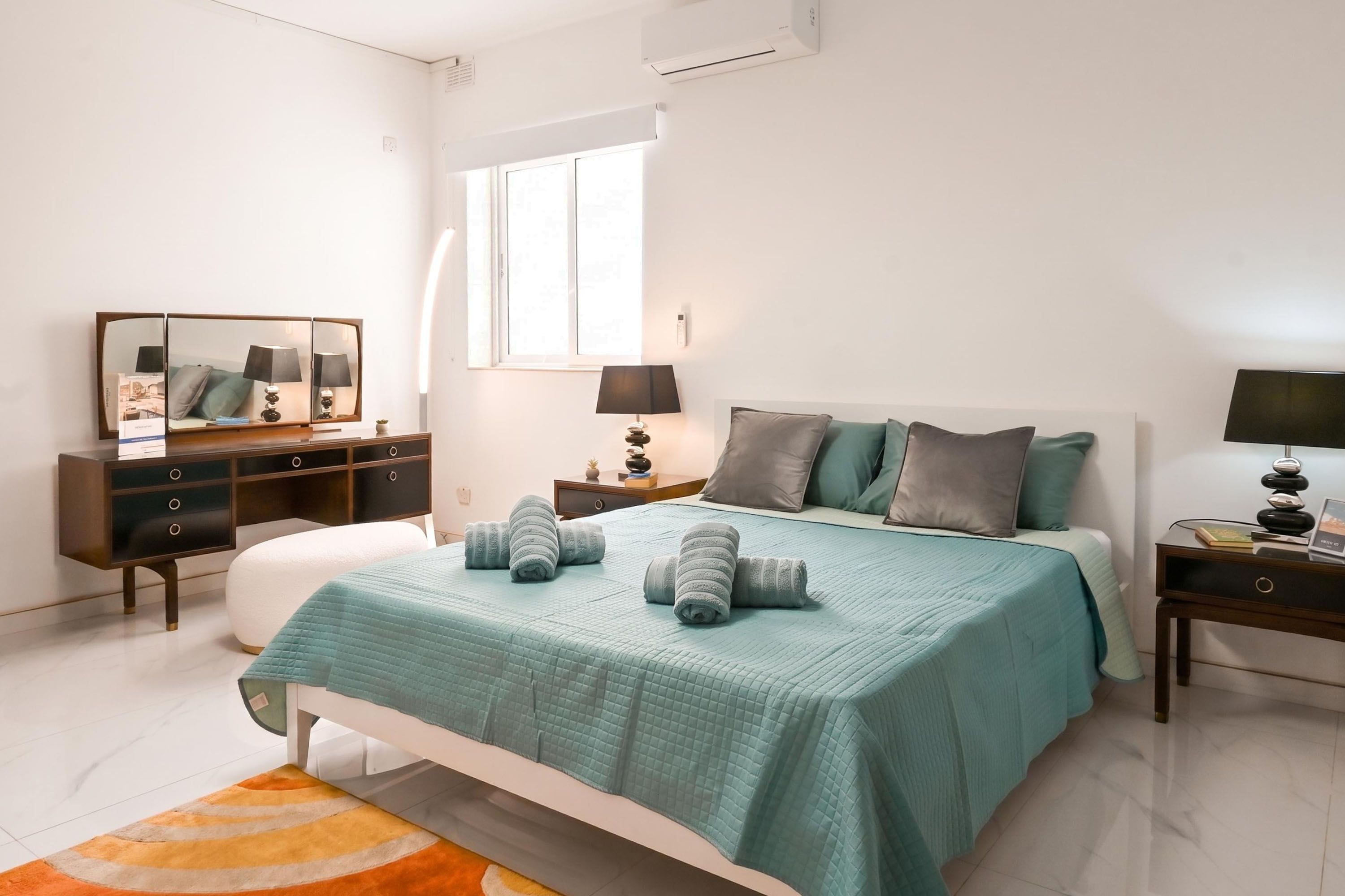 Una camera da letto con un letto, comodini, una cassettiera, uno specchio e una finestra.