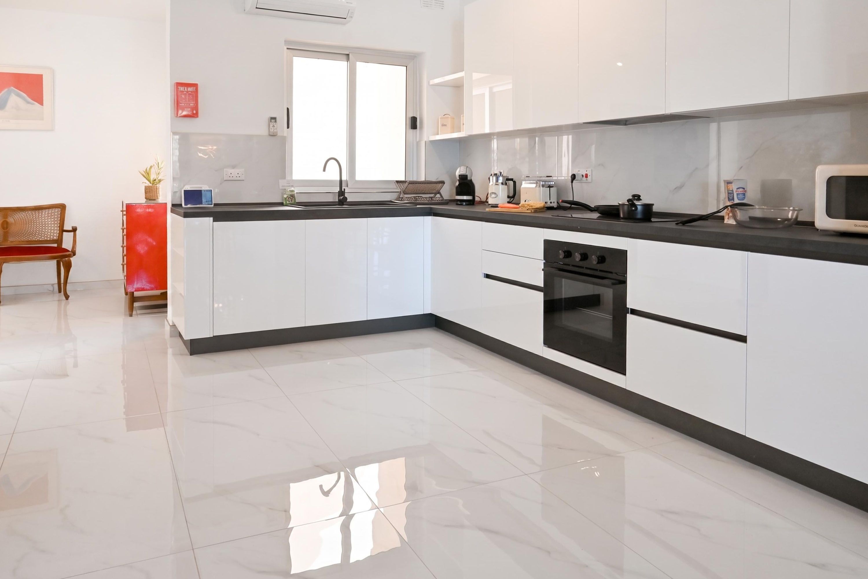 Een moderne keuken met witte kasten, een zwarte oven en een rvs aanrecht.