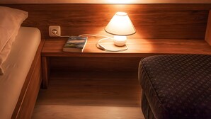 Ein Nachttisch aus Holz mit einer Lampe, einem Buch und einer Steckdose.