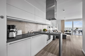 A modern kitchen with a Bosch coffee maker, a sink, and a stove. - Fernsicht: Breathtaking Baltic Sea Views & Modern Luxury (Wendtorf)