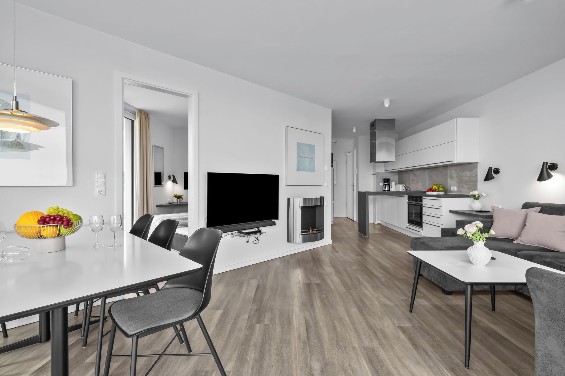 Ein moderner Wohnraum mit Essbereich, Flachbildfernseher, Kamin und Küche.