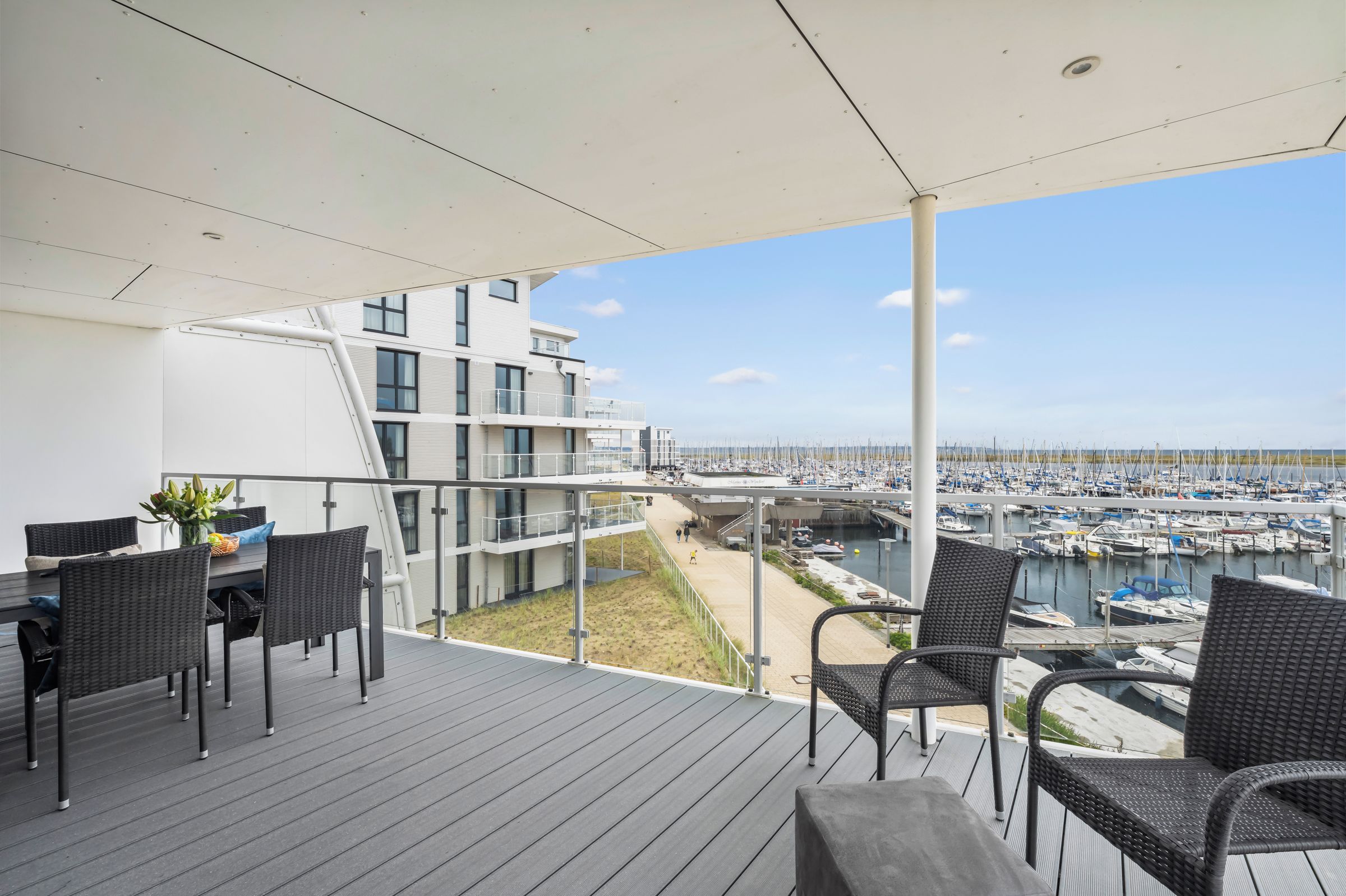 Un balcone con vista su un porto turistico e un edificio moderno.