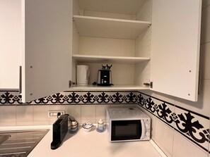 A kitchen with a microwave, toaster, and a coffee maker on the counter. - Gianicolo Hill Apartment (Roma)