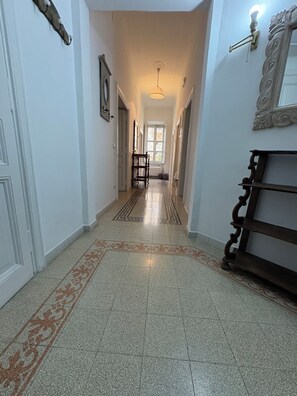 A hallway with a patterned floor, a bench, and a door on the left. - Gianicolo Hill Apartment (Roma)