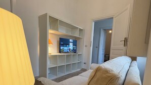 A living room with a TV, a sofa, a lamp, and a wooden floor. - Gianicolo Hill Apartment (Roma)