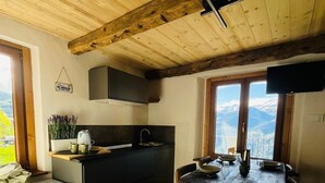Ett kompakt kök med matplats, synliga träbjälkar i taket och utsikt över bergen.