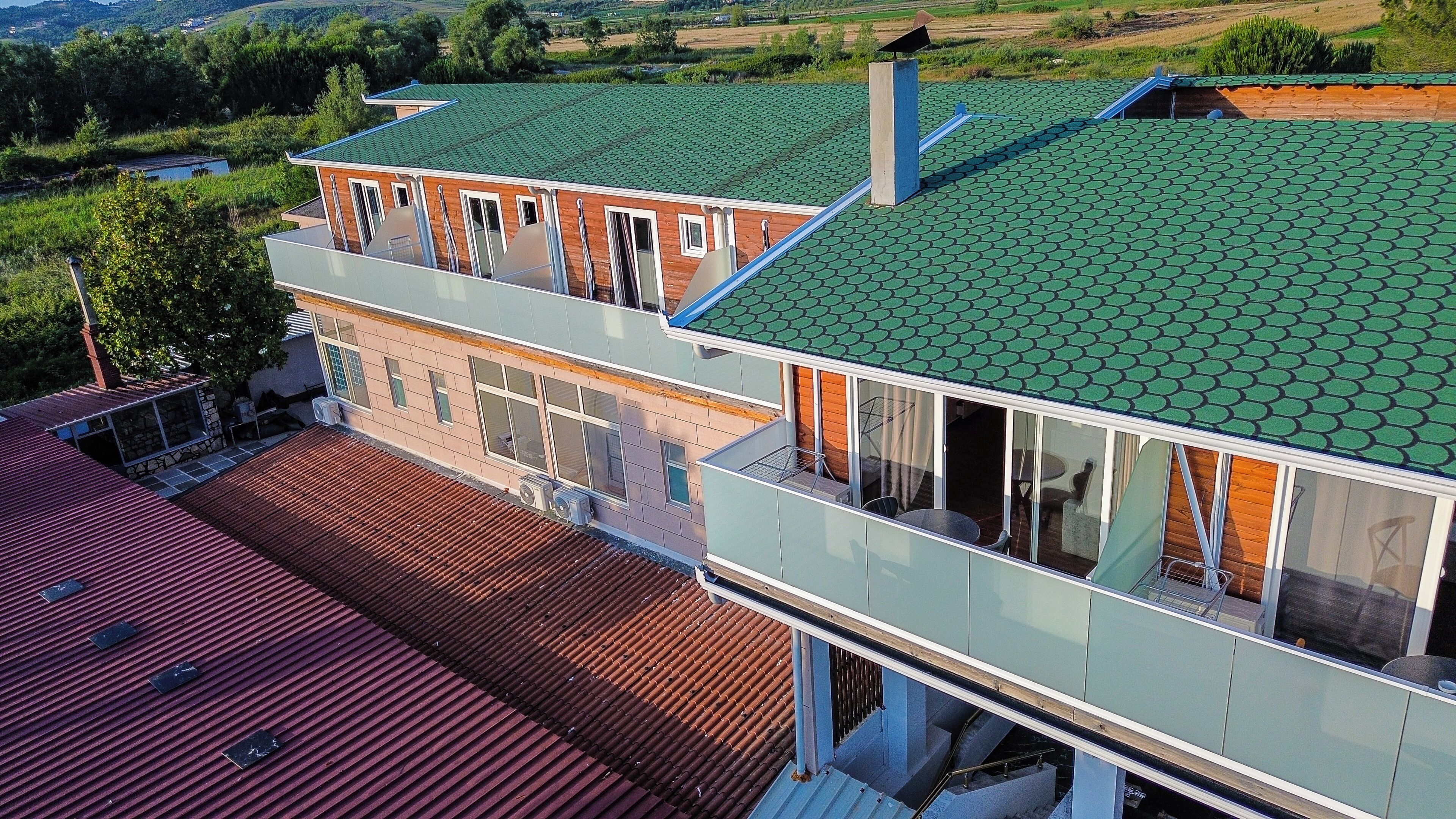 A two-story building with a green tiled roof, large windows, and a balcony.