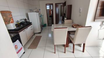 Una cocina moderna con gabinetes blancos, un refrigerador, una estufa y un comedor con mesa y sillas.