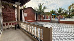 Un espacio al aire libre con diseño de cuadros, un balcón, un edificio de ladrillo y palmeras.