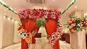 A hallway with a floral archway, red drapes, and a marble floor.