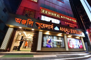 Un hôtel avec une enseigne indiquant « EENNRA ATTRAYEE BANQUET HALL » et « ANJALI JEWELLERS », ainsi qu’une grande publicité.