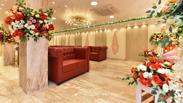 A hotel lobby with marble flooring, red sofas, and floral arrangements. - EENNRA ATTRAYEE GUEST HOUSE  & BANQUET (Balurghat)