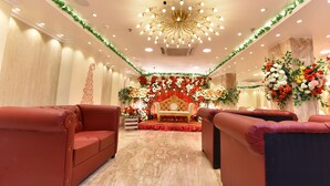 A room with a stage, red sofas, and a chandelier.