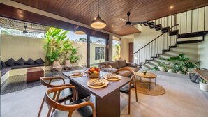 A modern interior with a dining area, staircase, and outdoor plants. - Nala Villa Bali (Badung)