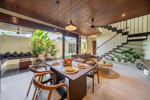 A modern interior with a dining area, staircase, and outdoor plants. - Nala Villa Bali (Badung)