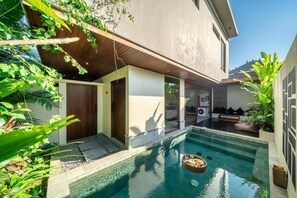 A modern house with a swimming pool, a wooden deck, and lush greenery. - Nala Villa Bali (Badung)