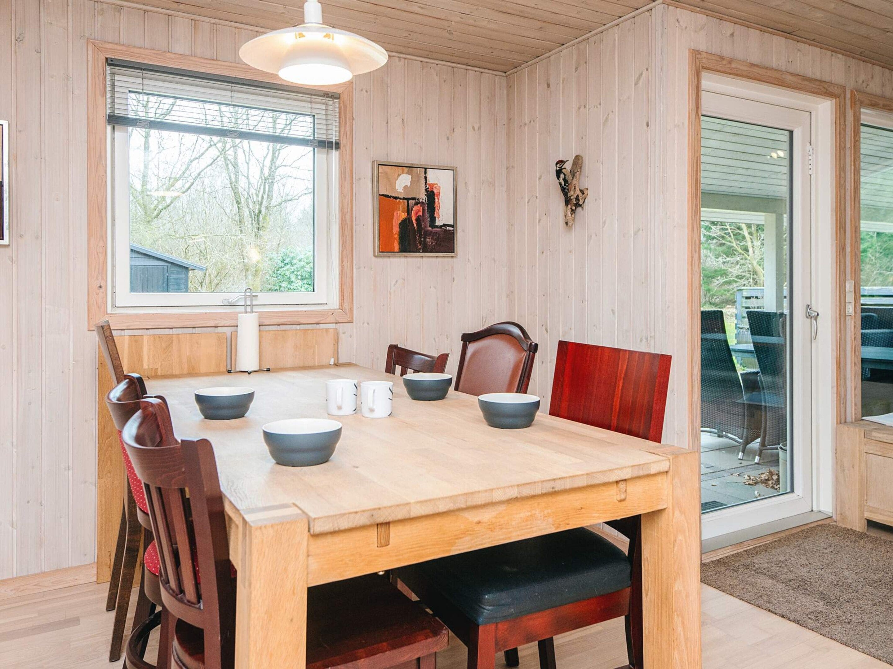 Ein Essbereich mit Holztisch, Stühlen und einem Fenster mit Jalousien.