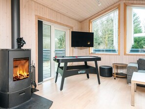 A room with a wood-burning stove, a pool table, a television, and a sofa. - 6 Person Holiday Home in Herning (Herning)