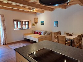 A cozy room with a bed, a dining table, and a kitchen area.