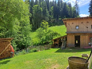 Une cabane en bois rustique, dotée d’une cour clôturée, d’une pile de bois de chauffage et d’un tonneau en bois.