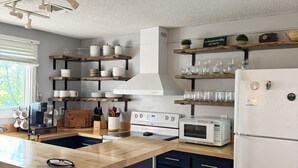 Eine moderne Küche mit einer zentralen Kochinsel, integrierten Geräten und Holzregalen.