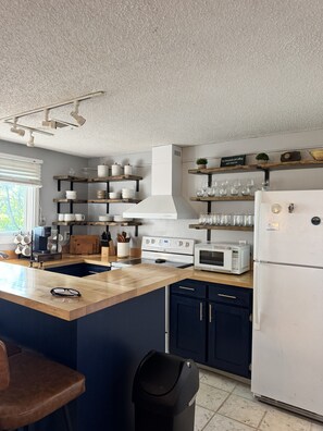 Una cocina moderna con una isla central, electrodomésticos integrados y estanterías de madera.