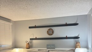 Ein Schlafzimmer mit einem Bett, zwei Nachttischen, einem an der Wand befestigten Regal, einem dekorativen Spiegel und einem Schild.