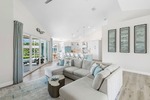 A modern living room with a sectional sofa, a coffee table, and a view to a dining area. - Bella Vista - 3BBR/3BA Coastal Retreat with Heated Pool & Spa (Marco Island)