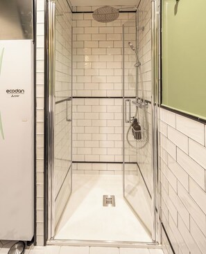 A glass-enclosed shower stall with white tiled walls and a green accent wall. - Ático Corazón de Madrid Apartamento B (Madrid)