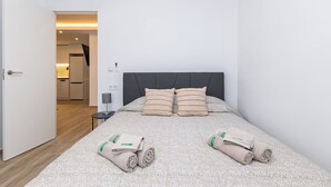 Une chambre à coucher avec un lit, des oreillers, une table de chevet et une serviette enroulée.