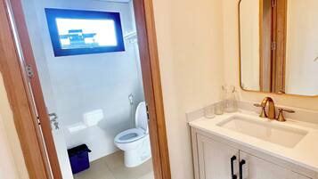 A bathroom with a toilet, sink, and mirror.