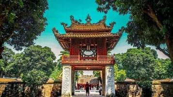 A traditional gate with intricate carvings, a paved pathway, and well-maintained greenery.