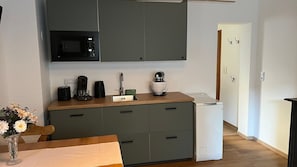 A compact kitchen with a microwave, coffee maker, and a small appliance on the counter.