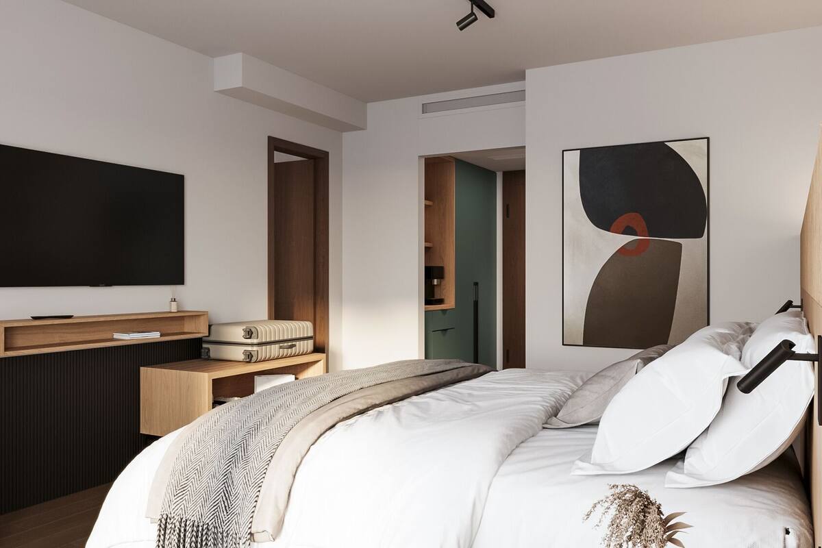Moderni hotellihuone, jossa on sänky, työpöytä, televisio ja taulu.