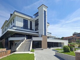 A modern multi-story building with a prominent vertical tower, large windows, and a staircase leading to the entrance.