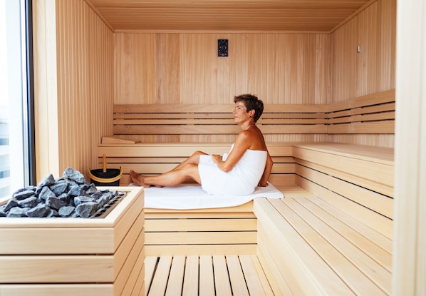 Una sauna con bancos de madera y una persona sentada en uno de ellos.