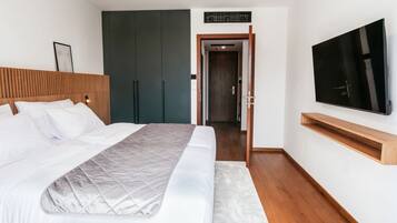 Ein modernes Schlafzimmer mit einem großen Bett, einem an der Wand befestigten Fernseher und einem Kleiderschrank.