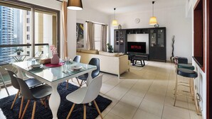 Un salon moderne avec une table à manger en verre, des chaises noires, un canapé et un téléviseur affichant le logo « NETFLIX ».