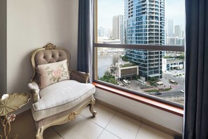 Ein Zimmer mit einem großen Fenster, einem bequemen Sessel und einem dekorativen Tisch.