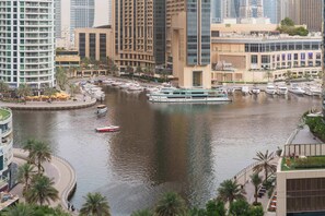 Ein Yachthafen mit Booten, einer Uferpromenade und modernen Hochhäusern.