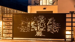 Fachada de edificio con diseño de silueta de árbol, muro de piedra y suelo de madera.