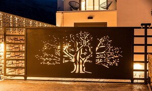 A building facade with a tree silhouette design, a stone wall, and a wooden floor. - Minoas Sky Villa Heated Pool (Lake Kournas)