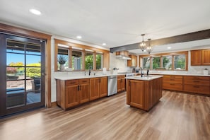A modern kitchen with wooden cabinets, a central island, and large windows. - Vintage 2BR Carlton retreat with hot tub, EV charging, and game room. (Carlton)