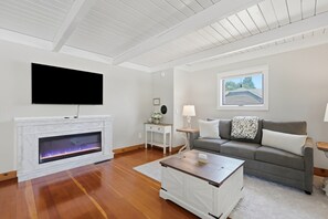 A living room with a fireplace, a flat-screen TV, a grey sofa, and a wooden coffee table. - Vintage 2BR Carlton retreat with hot tub, EV charging, and game room. (Carlton)