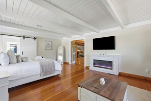 A modern bedroom with a bed, a wooden coffee table, a fireplace, and a TV mounted on the wall. - 5BR Carlton guesthouse with hot tub, patio, and fire pit (Carlton)