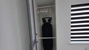 Un armario blanco con estantes, una barra para colgar ropa y un zapatero.